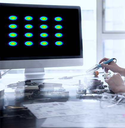 Hand holding a tool in front of a monitor with a coherent optical design